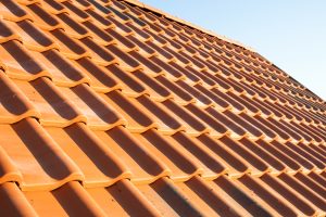 Overlapping rows of yellow ceramic roofing tiles covering residential building roof